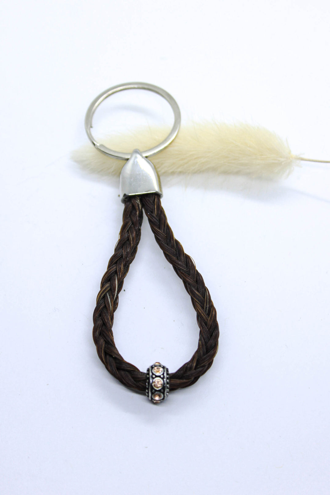 A braided horsehair keychain with a steel top and champagne sparkly bead