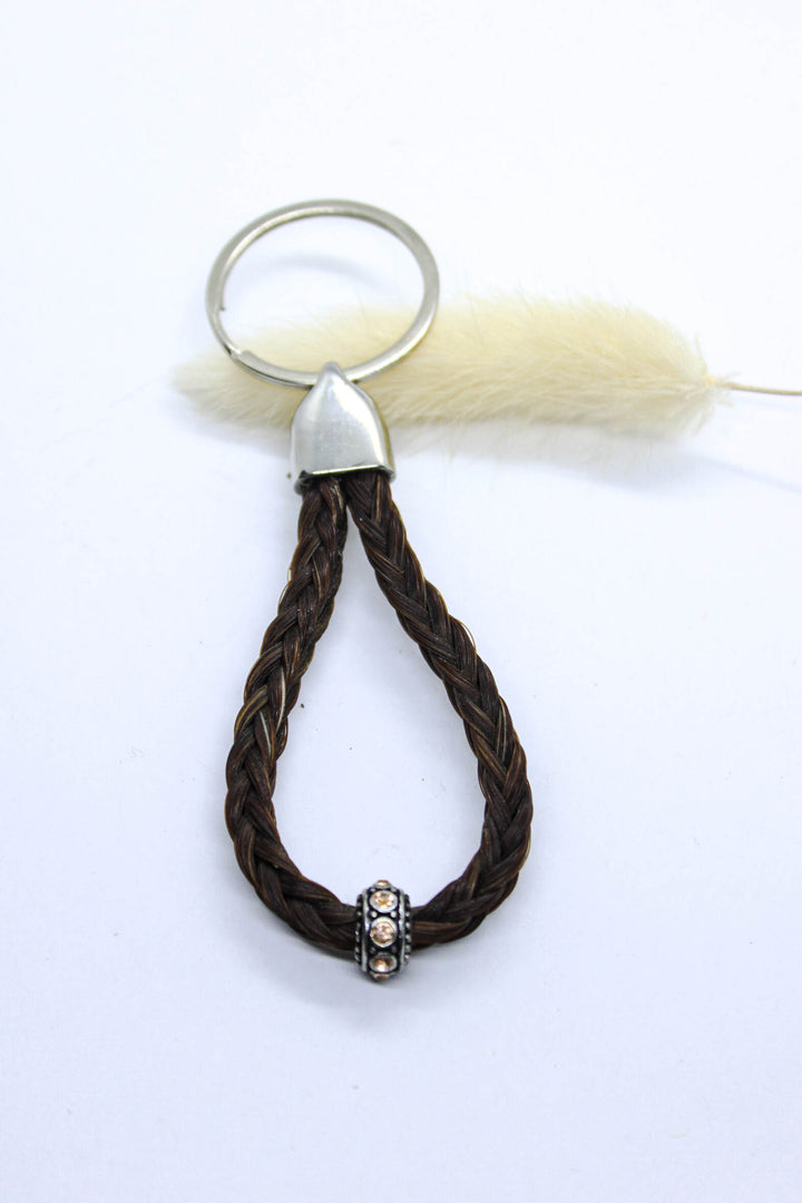A braided horsehair keychain with a steel top and champagne sparkly bead