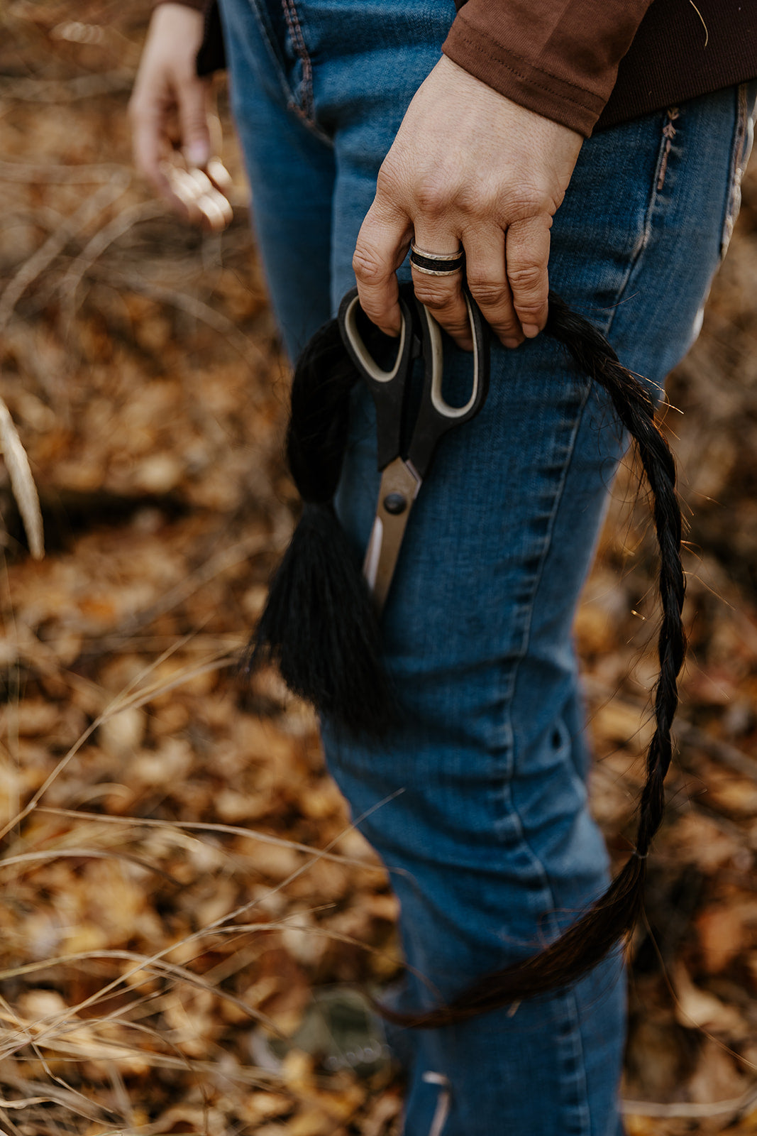 woman holding scissors and her horse's tail while wearing a custom ring made with horsehair
