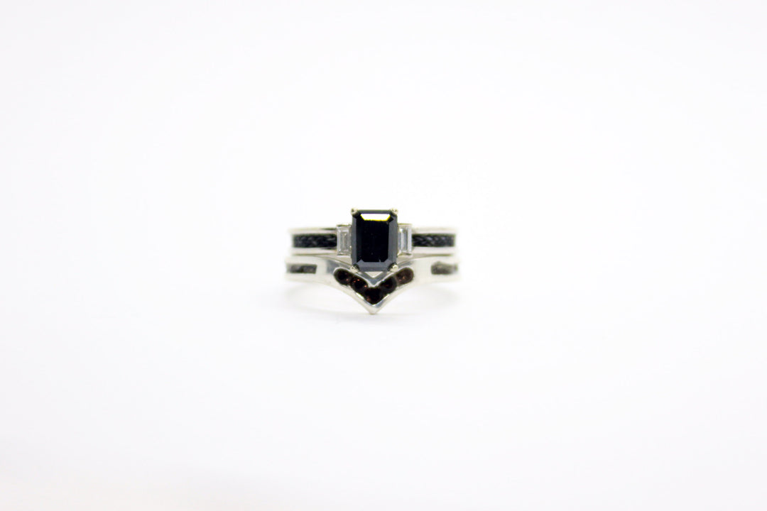 White gold, diamond and black diamond horsehair ring sitting on top of a white gold horsehair ring with smokey quartz stones, on a white background