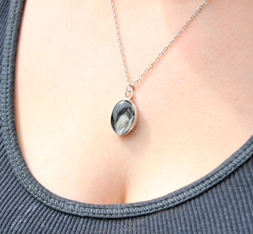 Close up of a woman wearing a glass oval pendant inlaid with horsehair