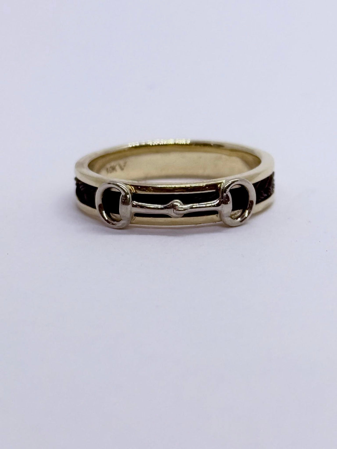 A white gold bit set on a yellow gold ring with woven horsehair set into the the ring