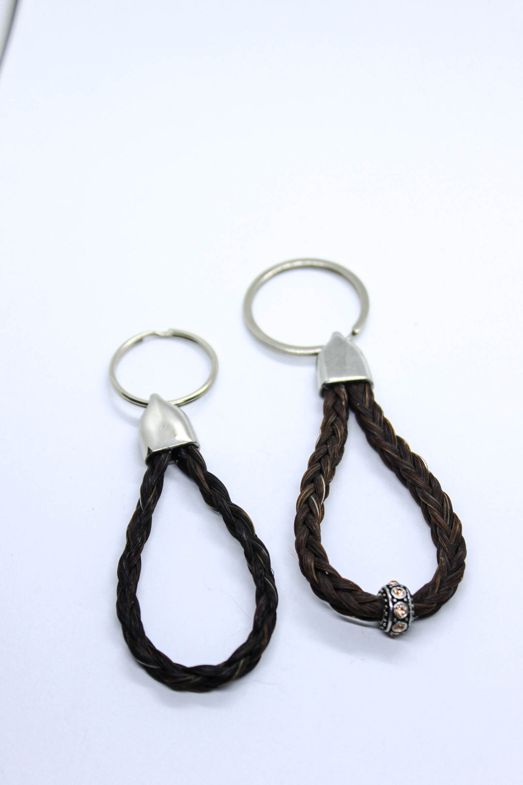 A black round braid horsehair keychain and a chestnut square braided horsehair keychain with bead